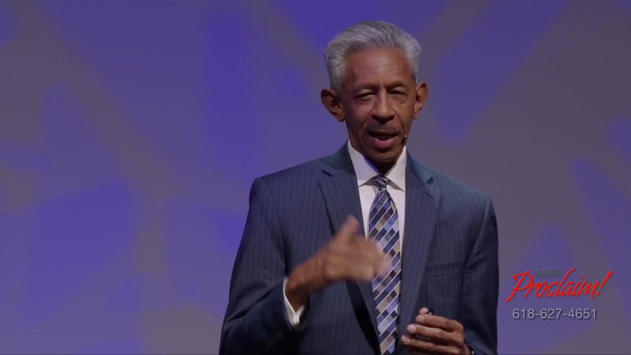 A man in a blue suit gestures with his right hand as he speaks. The 3ABN Proclaim! Network logo and a phone number are visible in the lower right corner.
