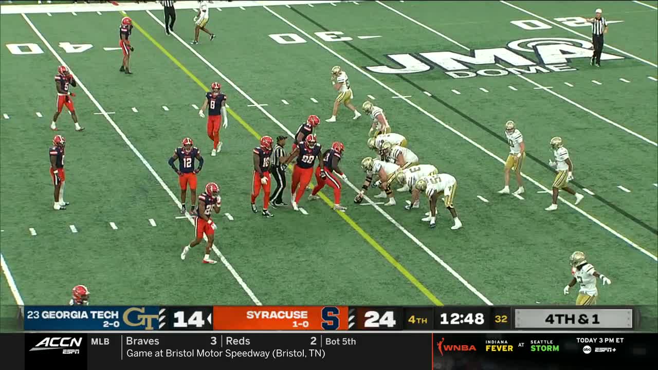 The Syracuse offense is lined up at the line of scrimmage, ready for a play. Georgia Tech's defense is spread out, anticipating the next move on the ACC Network broadcast.
