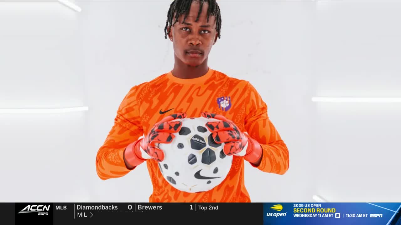 A soccer goalie, wearing an orange jersey and gloves, holds a soccer ball. The ACC Network logo is visible in the corner.
