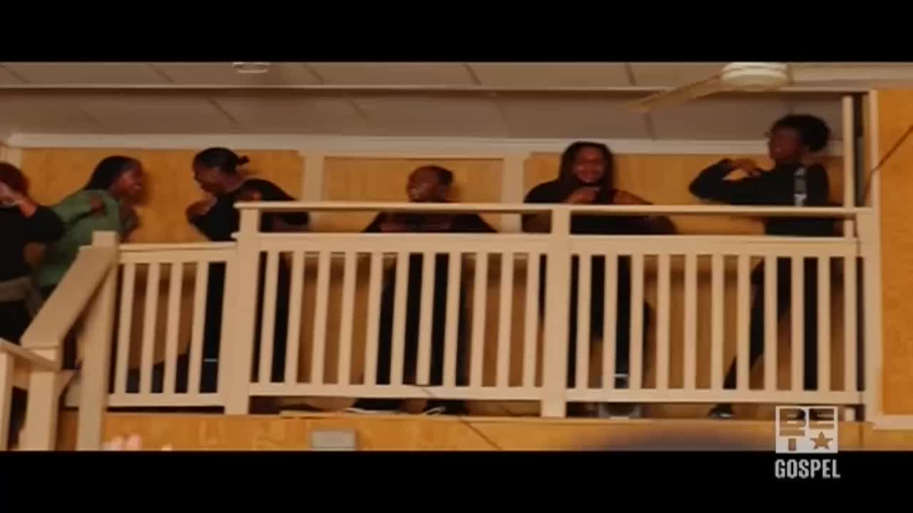 On a balcony, a group of people are gesturing and moving to the music. The energy is high, and the performers are clearly enjoying themselves.
