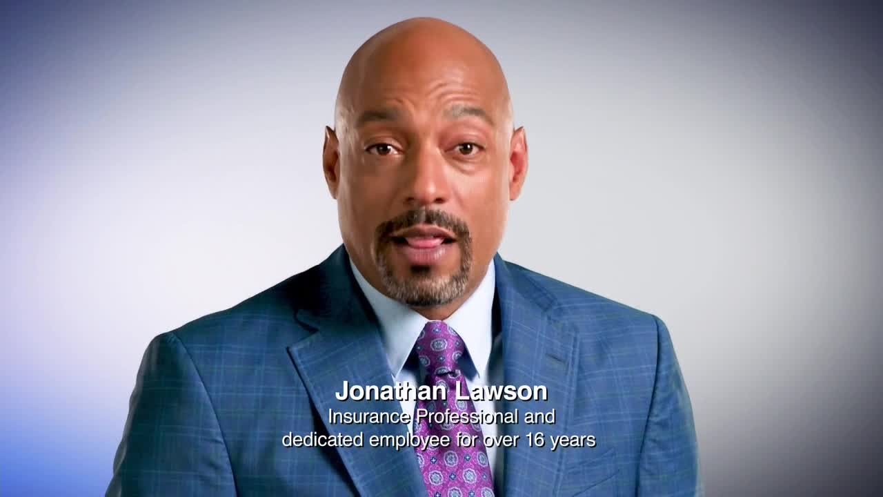 Jonathan Lawson, wearing a blue suit and patterned tie, looks directly at the camera with his tongue slightly out. His name and profession are displayed at the bottom of the screen.
