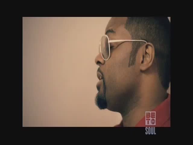 A man in white-rimmed glasses and a red shirt is speaking, his mouth slightly open. The BET Soul logo sits in the corner of the screen.
