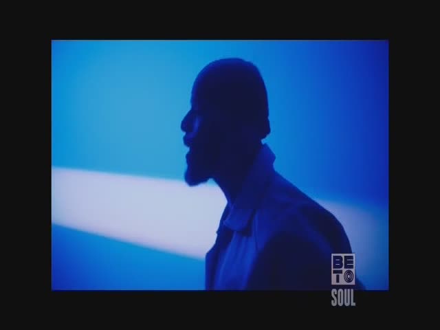 A man's silhouette is sharply defined against a bright blue backdrop, his face turned in profile. The BET Soul logo sits in the corner, suggesting a music video or performance.
