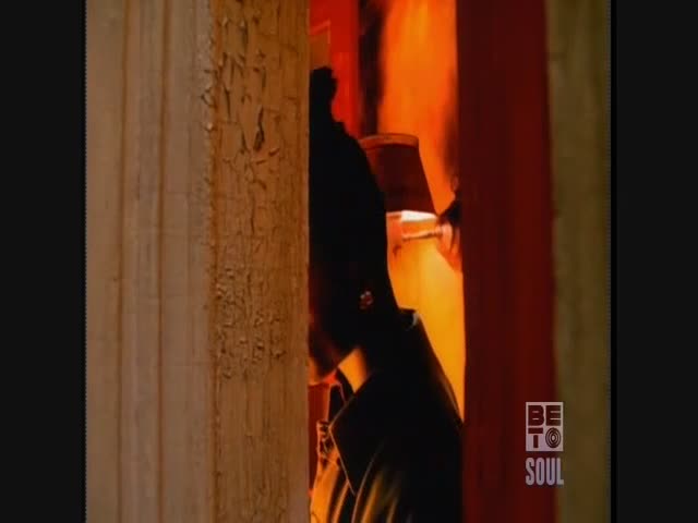 A figure, mostly in silhouette, stands in a doorway, the warm glow of a lamp illuminating the space behind them. The peeling paint on the wooden frame suggests an older building, maybe somewhere in the United States, and the "BET Soul" logo in the corner hints at a music video.
