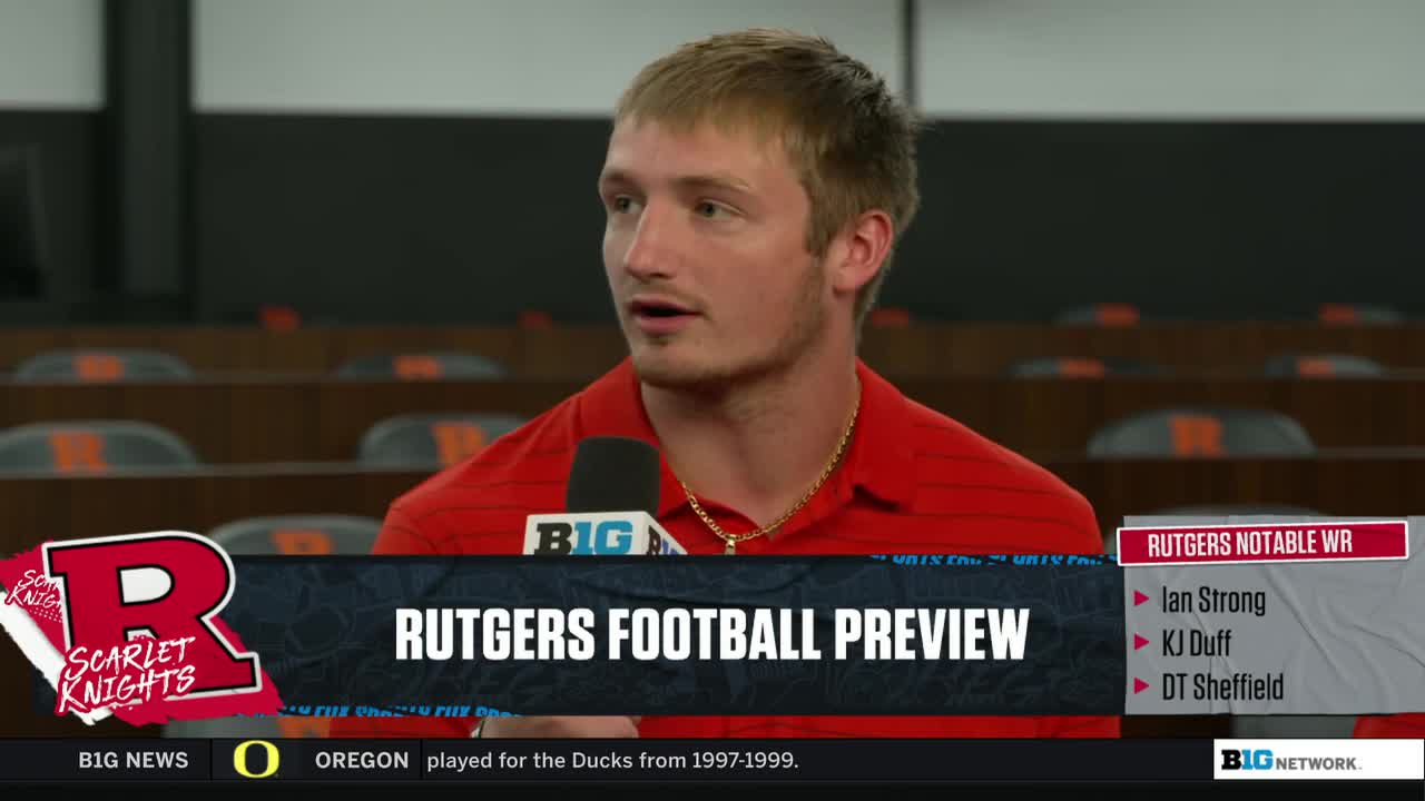 A man in a red shirt speaks into a microphone, likely on the Big Ten Network. Graphics on the screen identify the segment as a Rutgers football preview.
