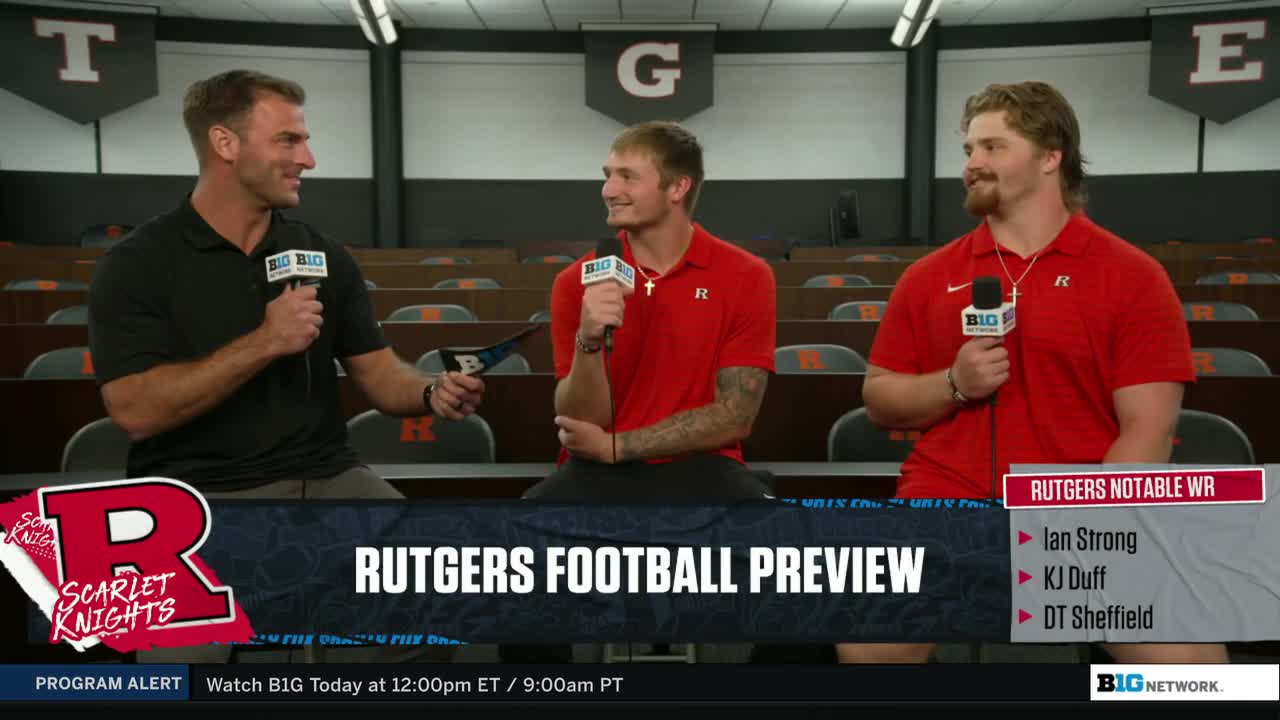 Three men in red Rutgers shirts are seated, each holding a microphone with a Big Ten Network logo. A "Rutgers Football Preview" graphic is displayed on the table in front of them.
