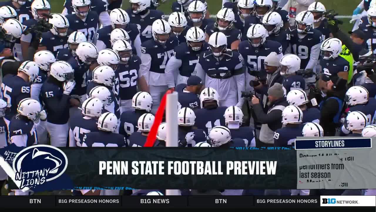The Penn State football team huddles together, their white helmets and blue jerseys a sea of color. Cameras and crew surround them, likely for a Big Ten Network preview.

