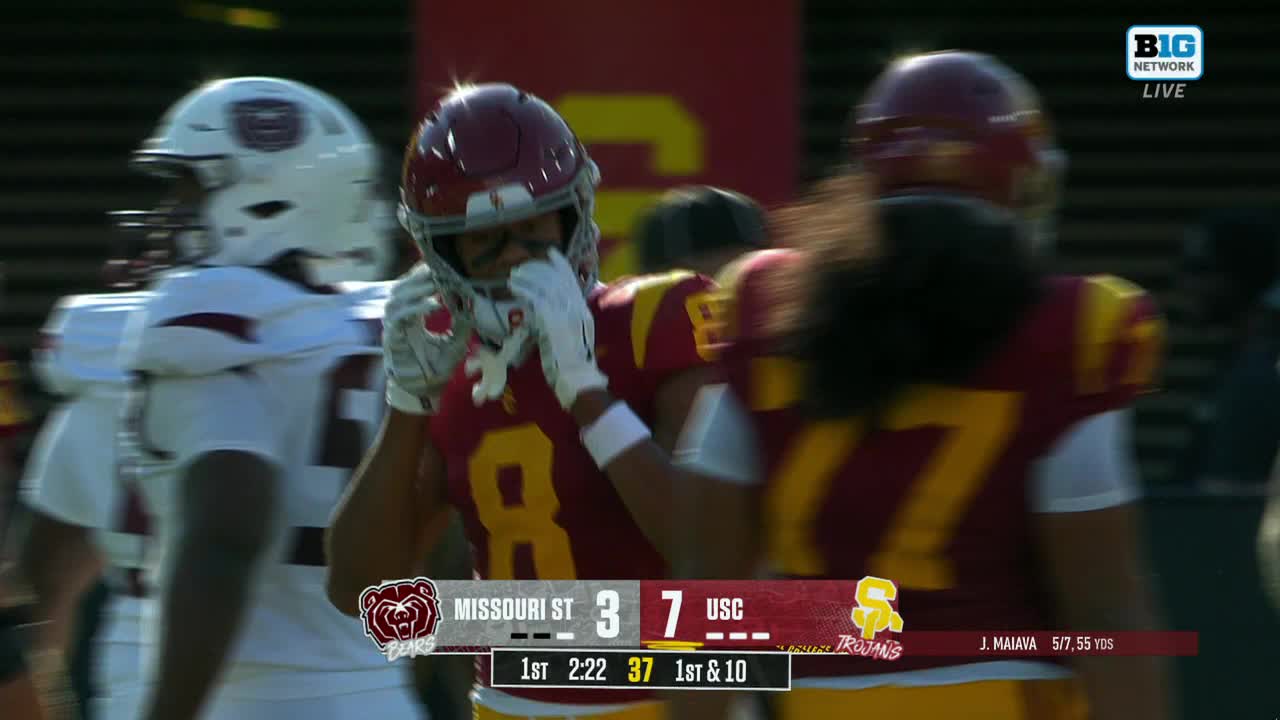 A USC player in a maroon helmet and jersey is wiping his face, while another teammate with long hair is partially visible. The Big Ten Network graphic shows the score and time remaining in the first quarter.
