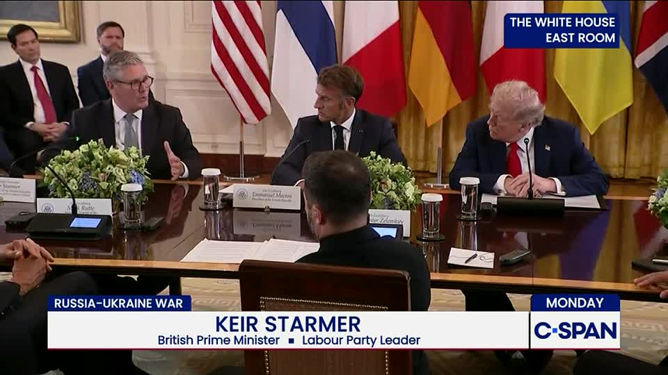 A man in a suit gestures emphatically, speaking to the others seated around the table. Across the table, a man in a red tie listens intently, while the C-SPAN logo sits in the corner.
