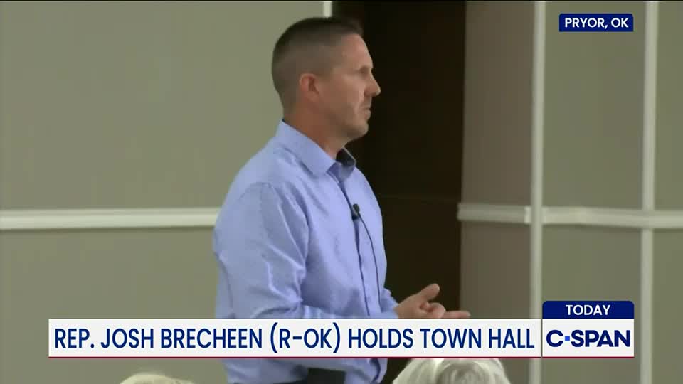 A man in a blue shirt gestures with his hands as he speaks, a microphone clipped to his collar. The C-SPAN logo identifies the event as a town hall in Pryor, Oklahoma, with Representative Josh Brecheen.
