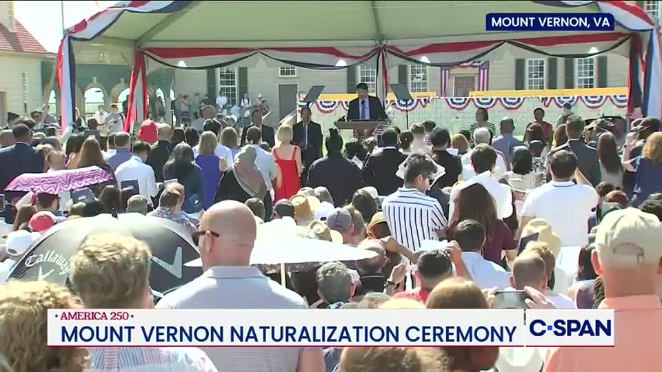 A crowd of people stands in front of a stage draped in red, white, and blue bunting. A man in a suit speaks at a podium, and the C-SPAN logo is visible in the corner.

