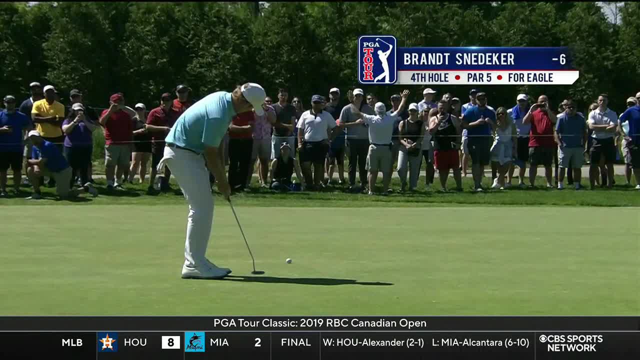 Brandt Snedeker, wearing a light blue shirt, is lining up a putt on the green, with the ball just ahead of his putter. The gallery behind him is already reacting, some with arms raised, as the CBS Sports Network USA coverage of the PGA Tour Classic unfolds.
