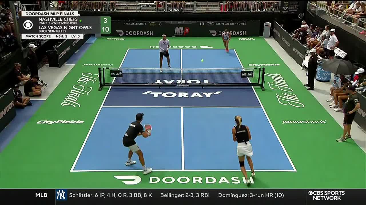 A pickleball match is underway, broadcast on CBS Sports Network USA, with the Las Vegas Night Owls leading. The ball hangs in the air as players prepare to return it.
