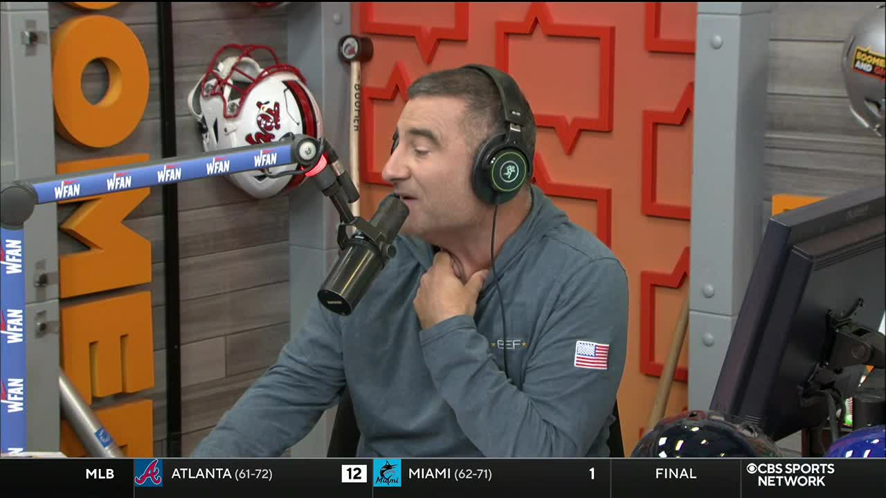 A man wearing headphones speaks into a microphone, gesturing with his hand near his neck. The CBS Sports Network USA logo is visible in the lower right corner.
