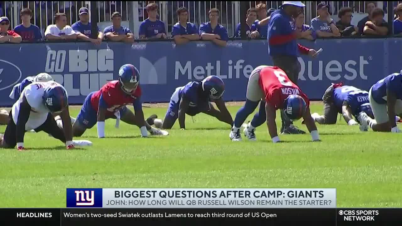 On the CBS Sports Network USA broadcast, New York Giants players are stretching on the field. They're in a low, bent-over position, with their hands on the ground.
