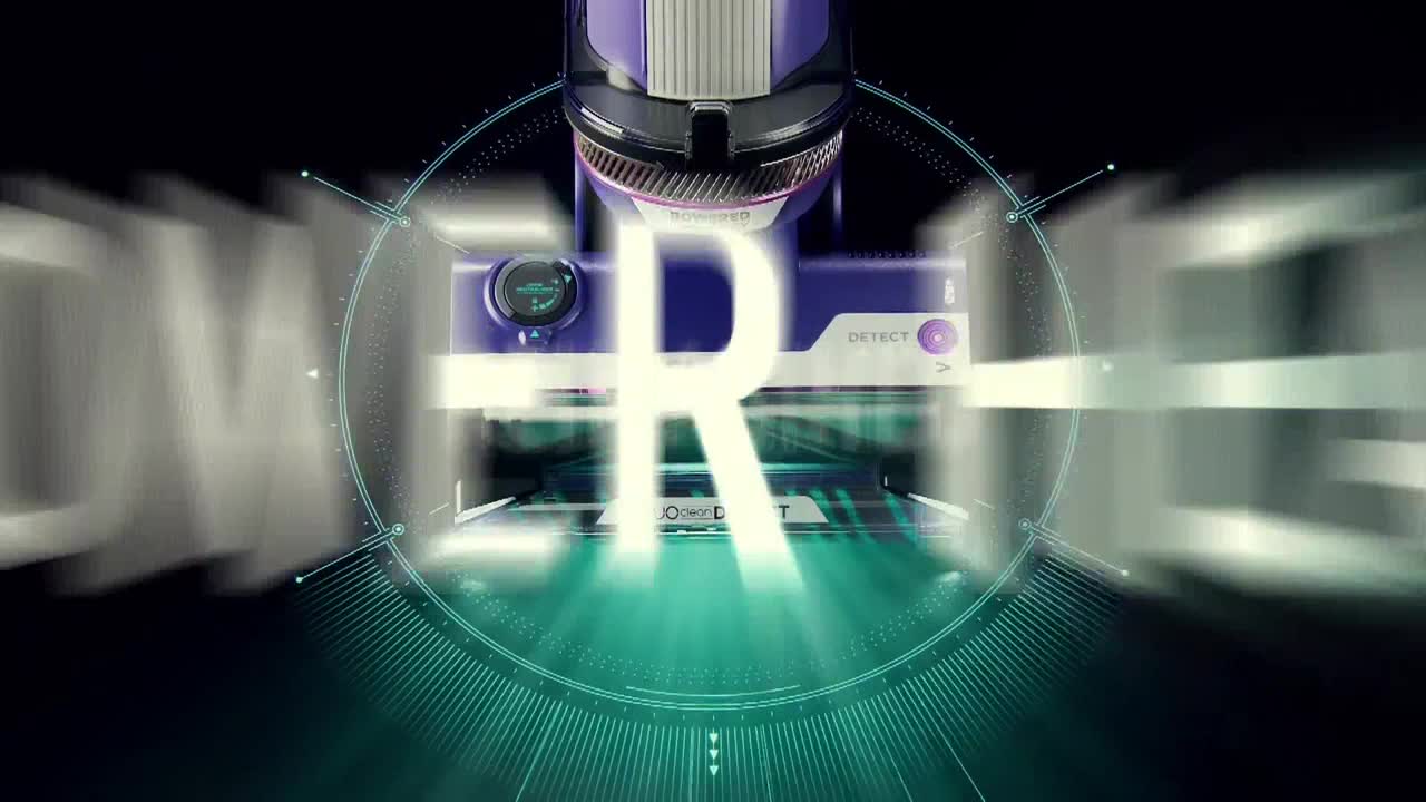 A purple and silver machine sits center stage, with the letter "R" glowing brightly over its surface. The word "COMEDY" is partially visible, zooming in from the left.
