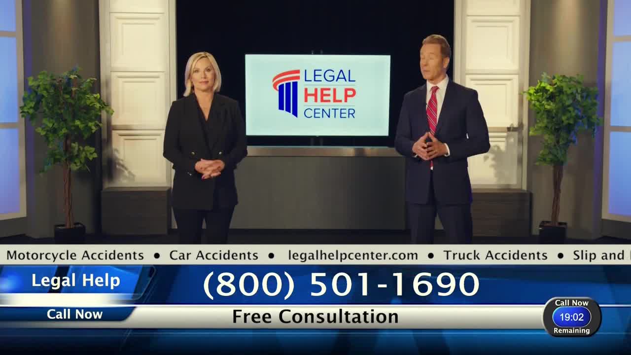 A man in a suit and a woman in a black blazer stand in front of a screen with a law firm's logo. Below them, a phone number flashes, and a timer ticks down.
