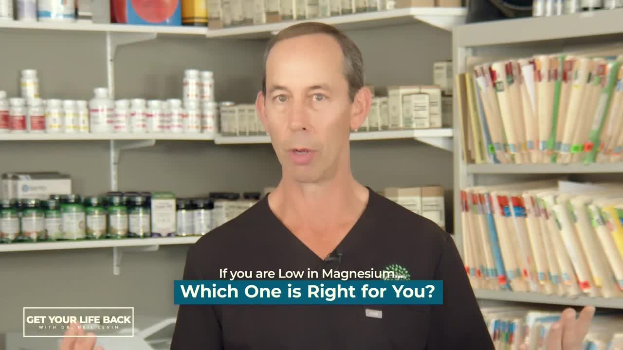 A man in a black shirt is speaking, gesturing with his hands in front of shelves filled with bottles and files. Below him, text on a blue box asks about magnesium.
