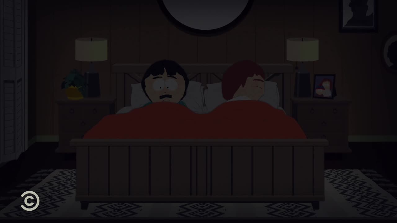 Randy Marsh looks wide-eyed, staring up from under a red blanket. His wife, Sharon, sleeps soundly beside him in their bed.
