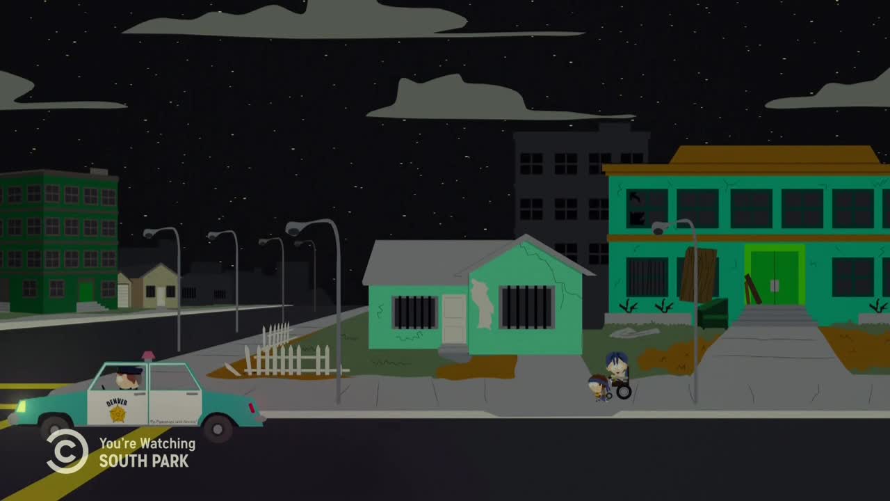 A police car speeds down the street, its lights flashing in the dark. Two figures, one in a wheelchair, stand on the sidewalk near a building with boarded-up windows, a scene from *South Park* on Comedy Central.
