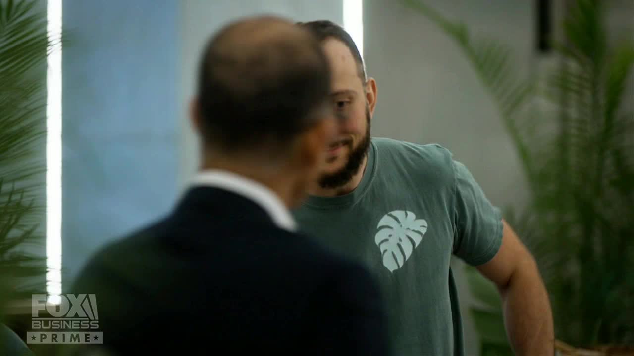 A man in a green shirt with a leaf design smiles at someone off-camera. The Fox Business Network logo is visible in the lower left corner.
