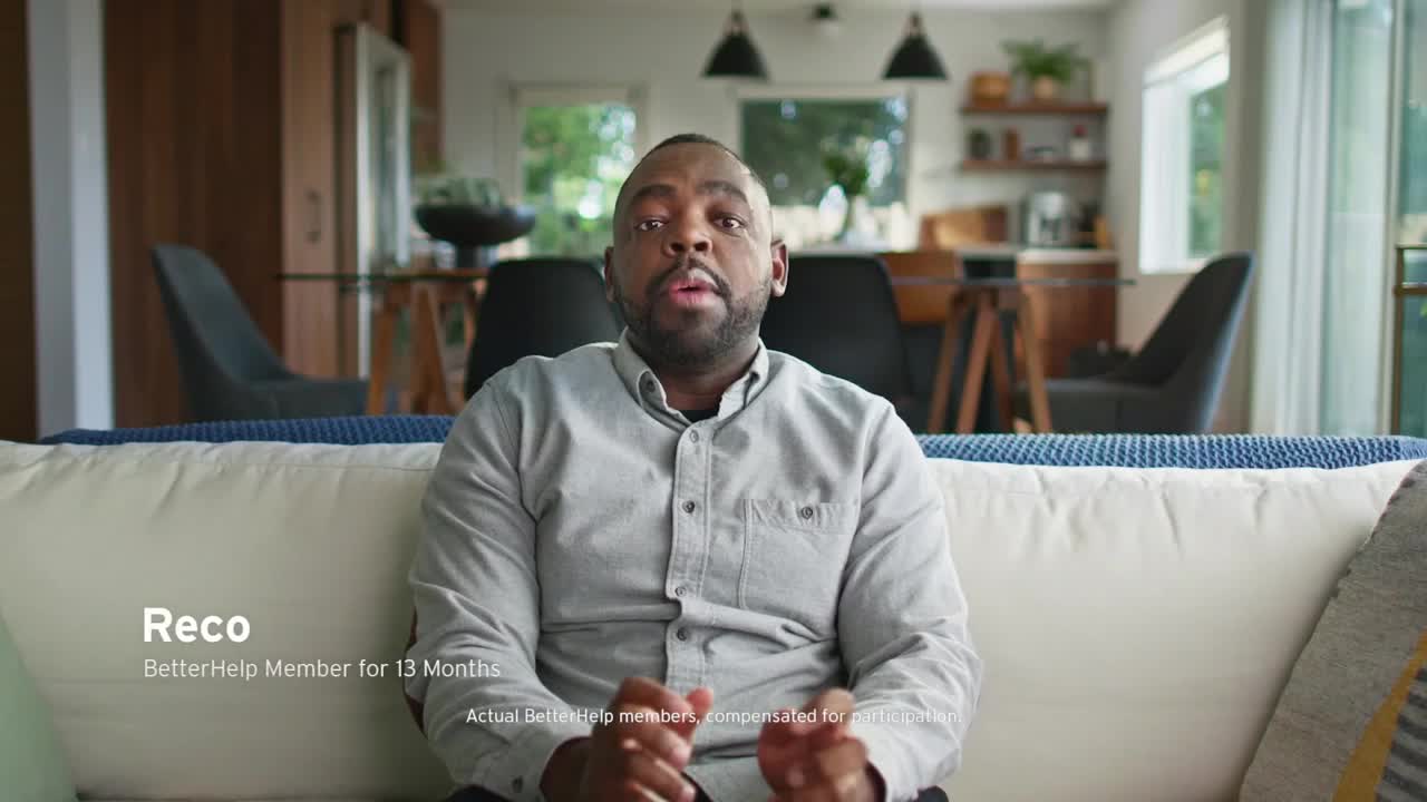 Reco, a BetterHelp member, is sitting on a couch and speaking directly to the camera. The Game Show Network advertisement features him in what appears to be his living room.
