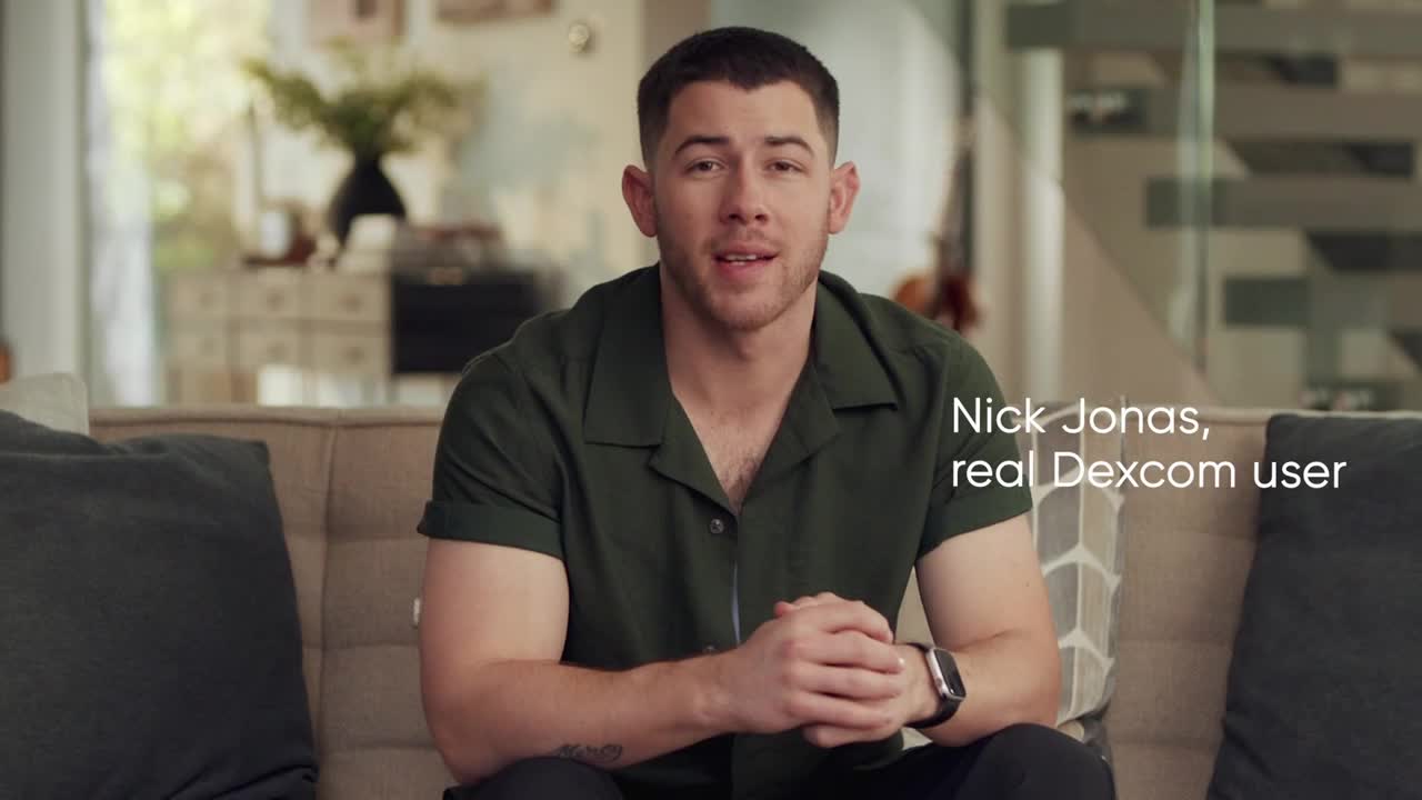 Nick Jonas sits on a couch, looking straight at the camera. A caption identifies him as a "real Dexcom user."
