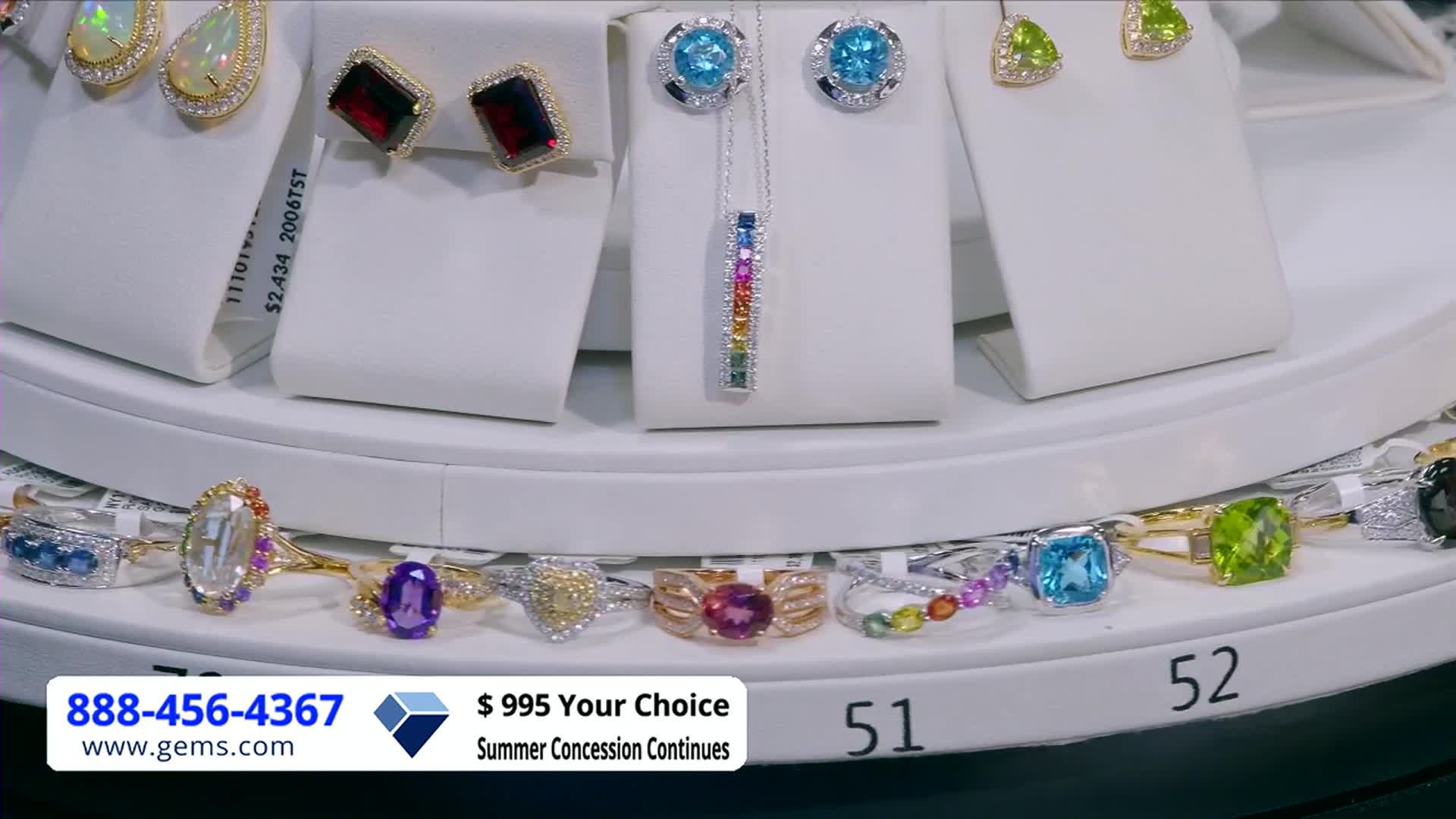 A rotating display showcases jewelry, from earrings to rings, under bright studio lights. The Gem Shopping Network logo and a phone number are visible at the bottom.
