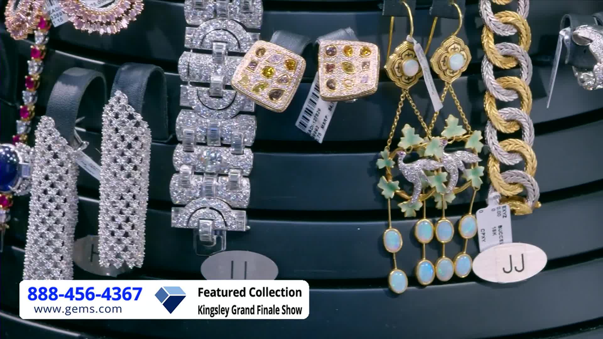Jewelry sparkles under bright lights, arranged on a display for the Gem Shopping Network. A pair of earrings with dangling opals and a bird design catches my eye.
