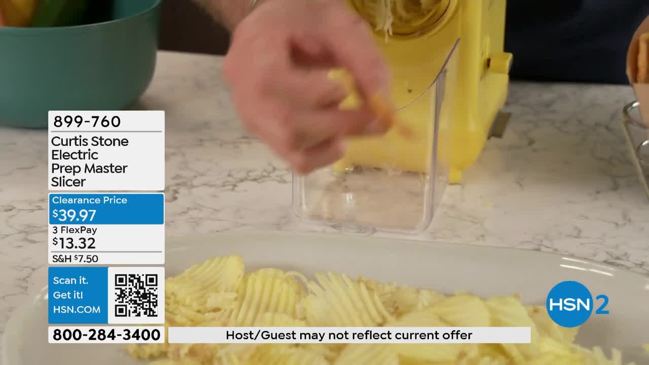 A hand guides a piece of food into a yellow electric slicer, creating ruffled slices that fall onto a white platter. The HSN2 logo appears in the lower right corner.