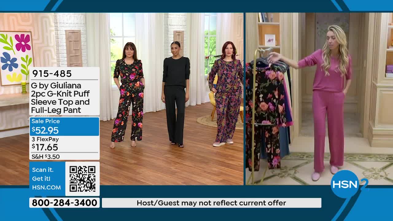 A woman in a floral pajama set walks across the stage. Another woman, dressed in solid pink loungewear, gestures towards a rack of clothing.