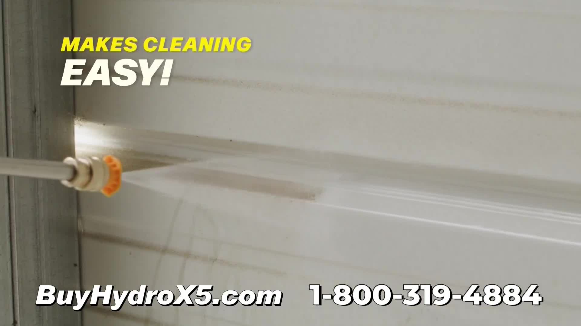 A high-pressure nozzle sprays a stream of water across a dirty, corrugated surface. The water blasts away the grime, leaving a clean streak behind.
