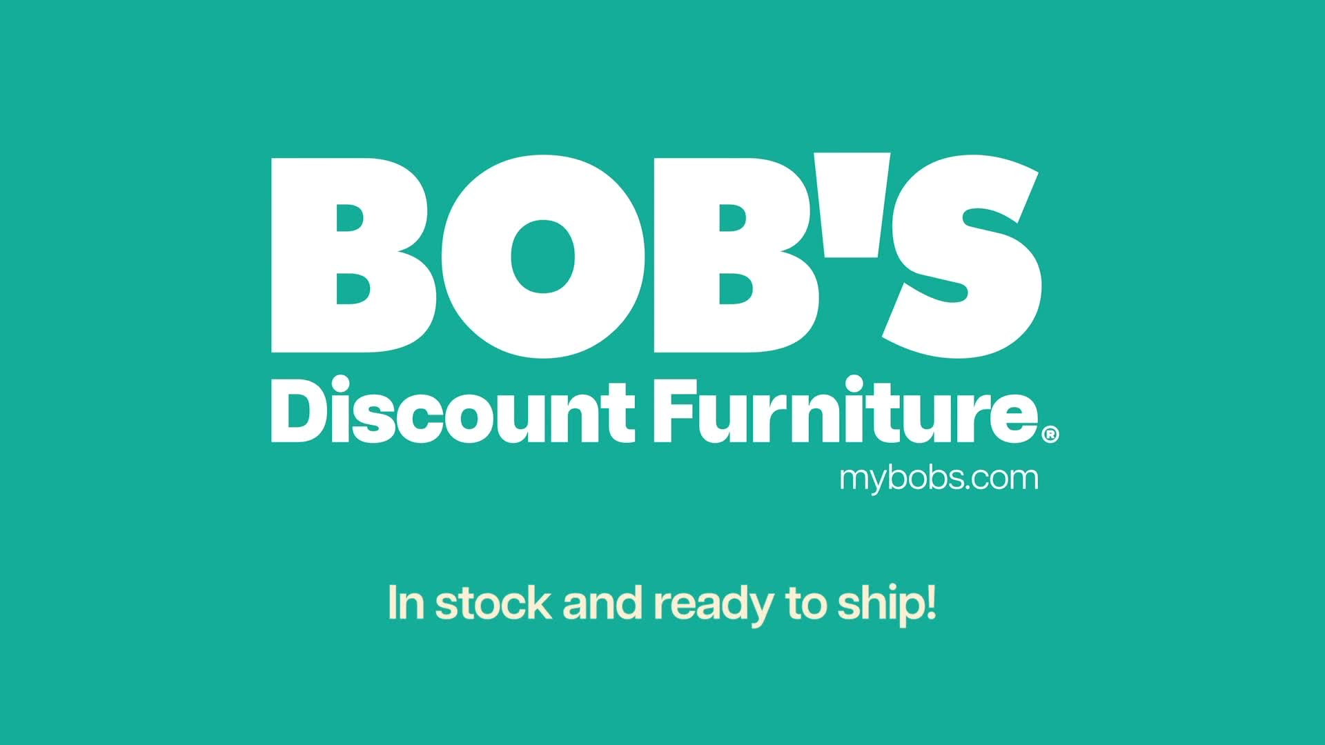 The large white letters "BOB'S Discount Furniture" dominate the screen. Below that, "mybobs.com" is written in smaller white text, and at the very bottom, "In stock and ready to ship!" is displayed.