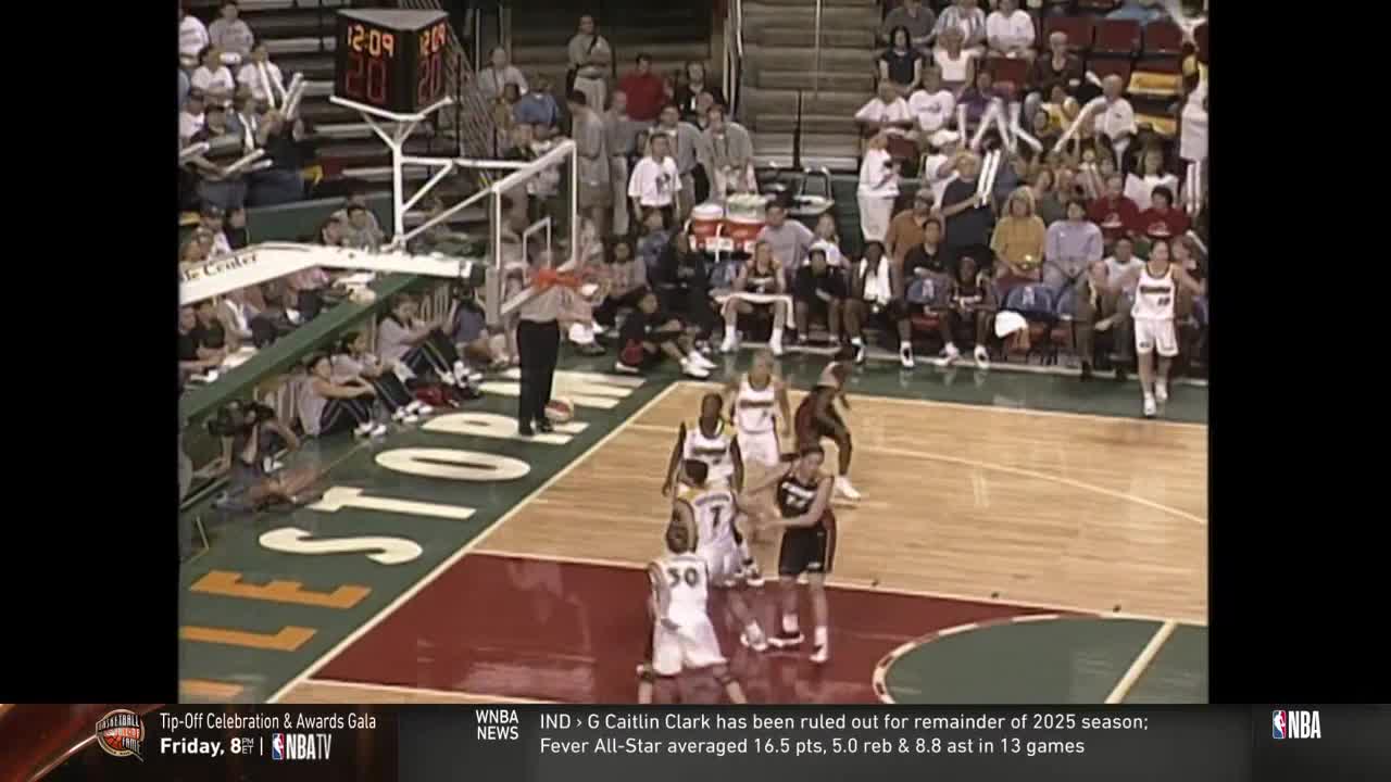 The referee stands near the basket, signaling with his arms as several players cluster around. The clock shows just over twelve minutes remaining in the game, broadcast on NBA TV.

