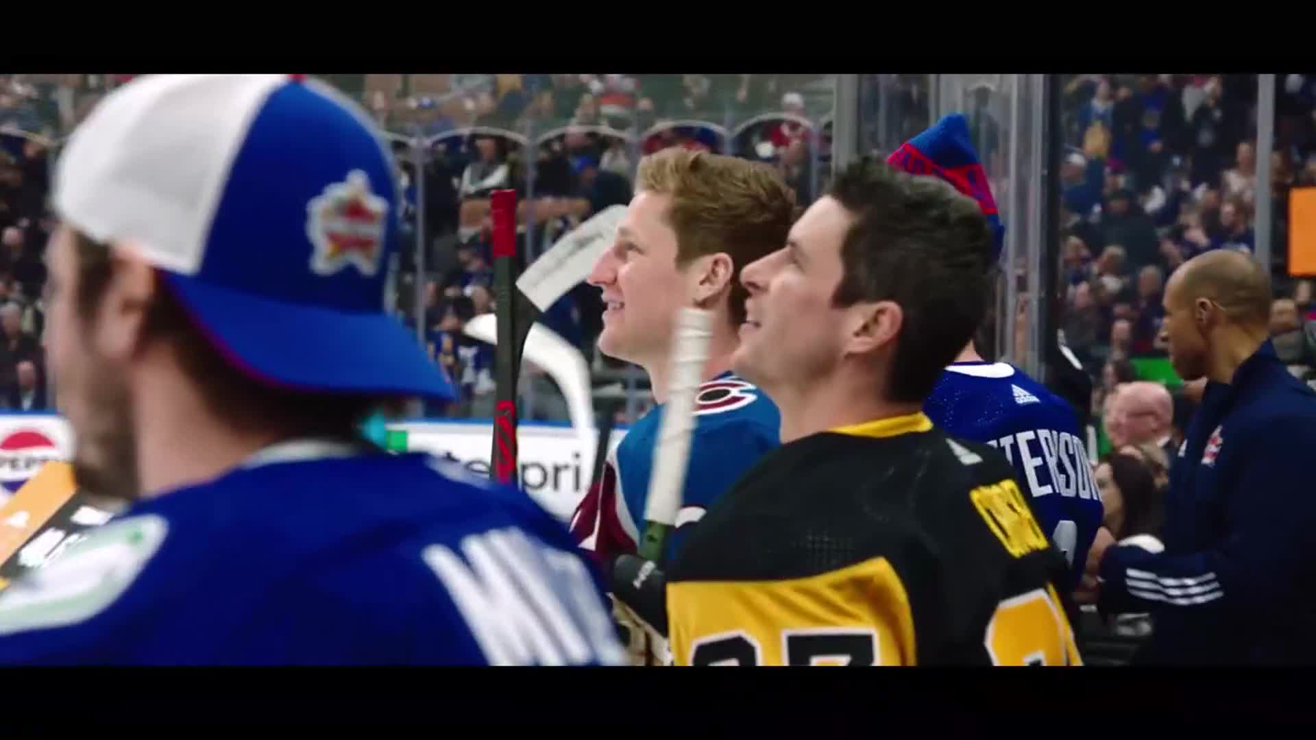 A group of hockey players stand on the ice, their sticks held loosely. The crowd in the stands behind them is a sea of faces.