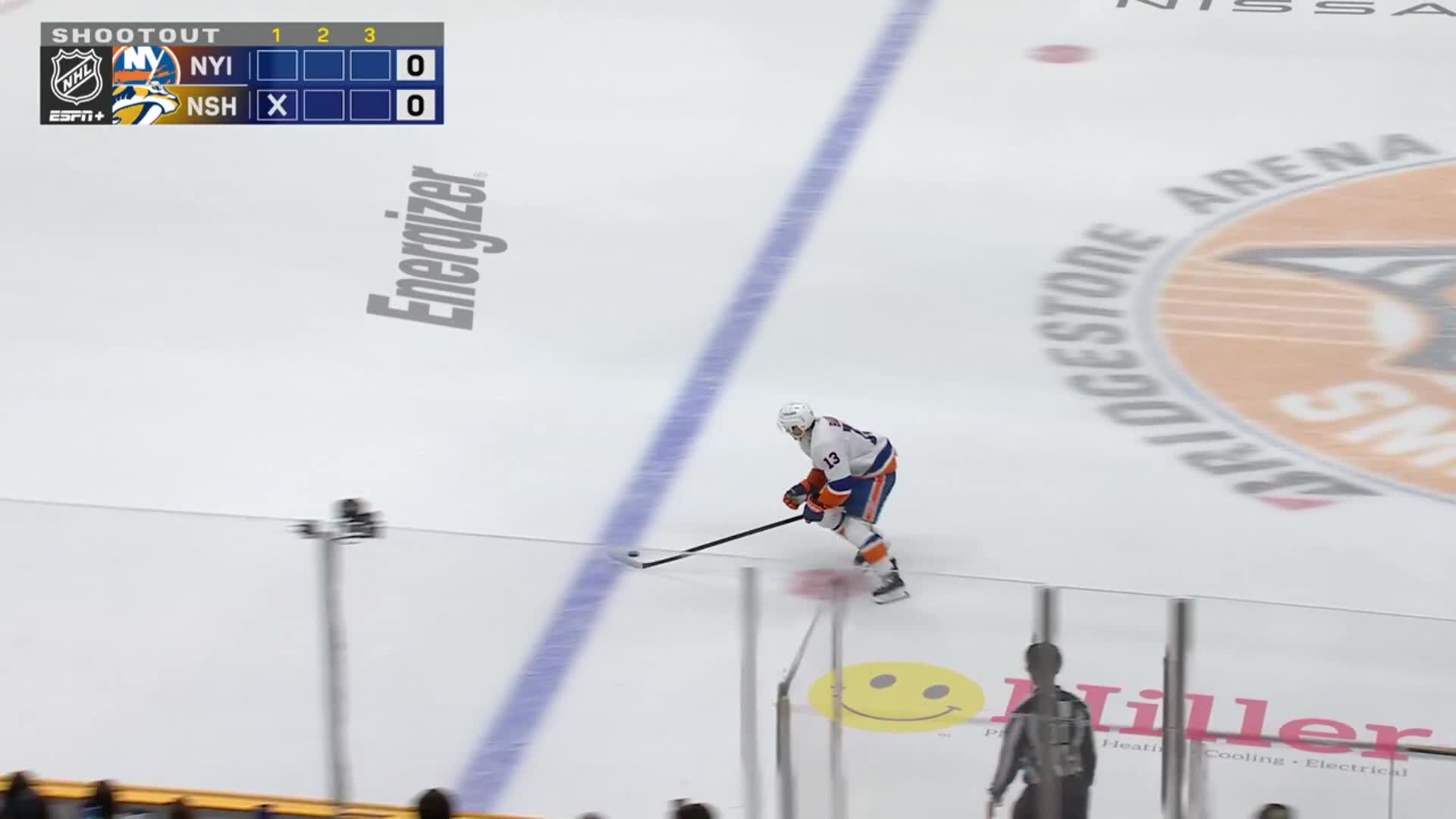 A New York Islanders player skates down the ice during a shootout. The scoreboard shows both teams tied at zero.
