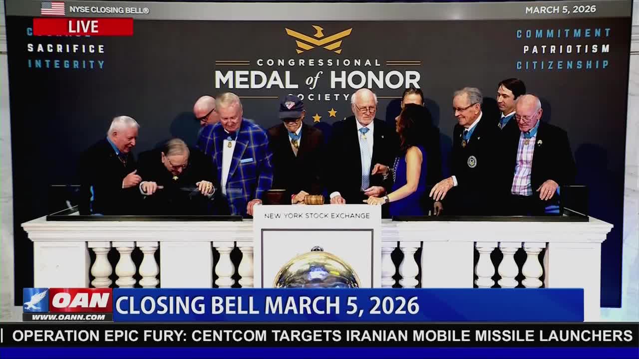 Several men, some in suits and medals, gather around a table at the New York Stock Exchange. One man leans forward, appearing to ring a bell. The OAN broadcast banner displays "CLOSING BELL MARCH 5, 2026."