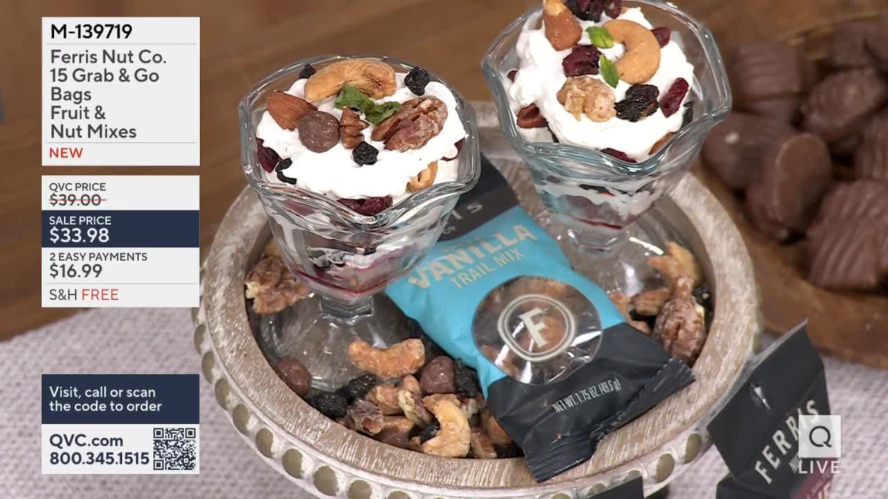 Two clear glasses hold layered desserts topped with nuts and dried fruit. A small bag of vanilla trail mix sits beside them, surrounded by loose nuts and chocolates.