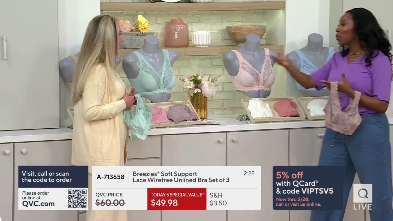 A woman in a purple top holds up a lacy pink bra, gesturing towards mannequins displaying similar styles. Another woman in a cream cardigan stands beside her, holding a mint green bra.