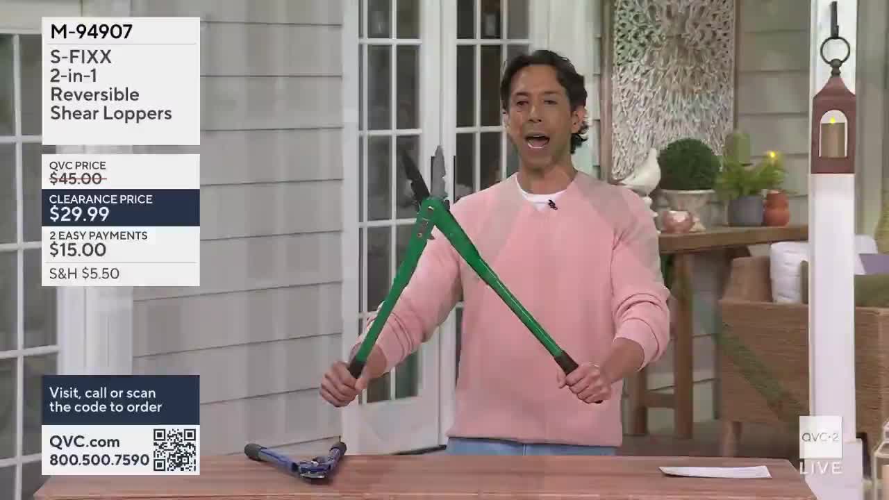 A man on QVC2 holds up a pair of large, green-handled loppers, demonstrating their size. Another pair of blue loppers rests on the table in front of him.