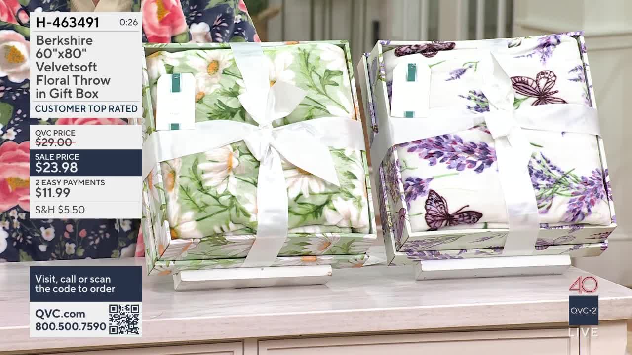 Two gift boxes, each containing a folded throw blanket, sit side-by-side. The box on the left displays a daisy pattern, while the one on the right features lavender and butterflies.