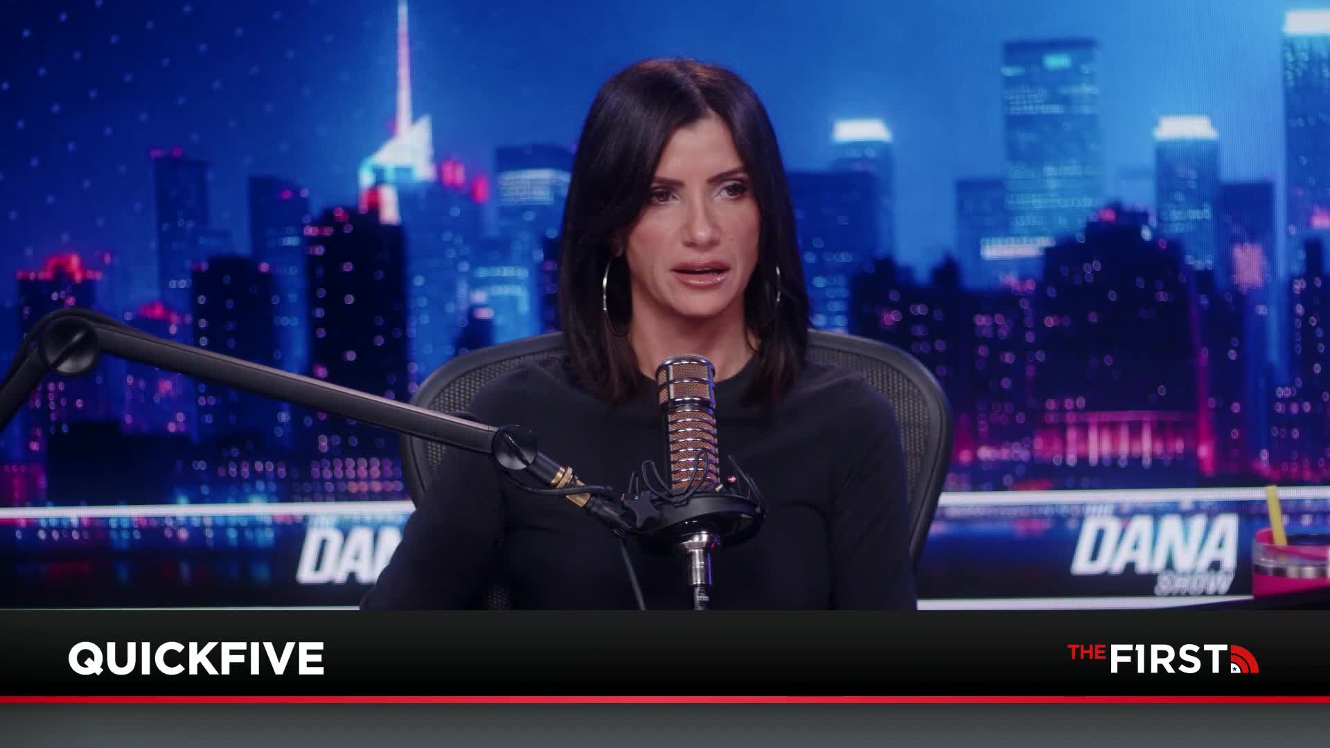 A woman with dark hair speaks into a microphone in front of a backdrop of a city skyline. A graphic at the bottom of the screen reads "QUICKFIVE" and "THE FIRST."