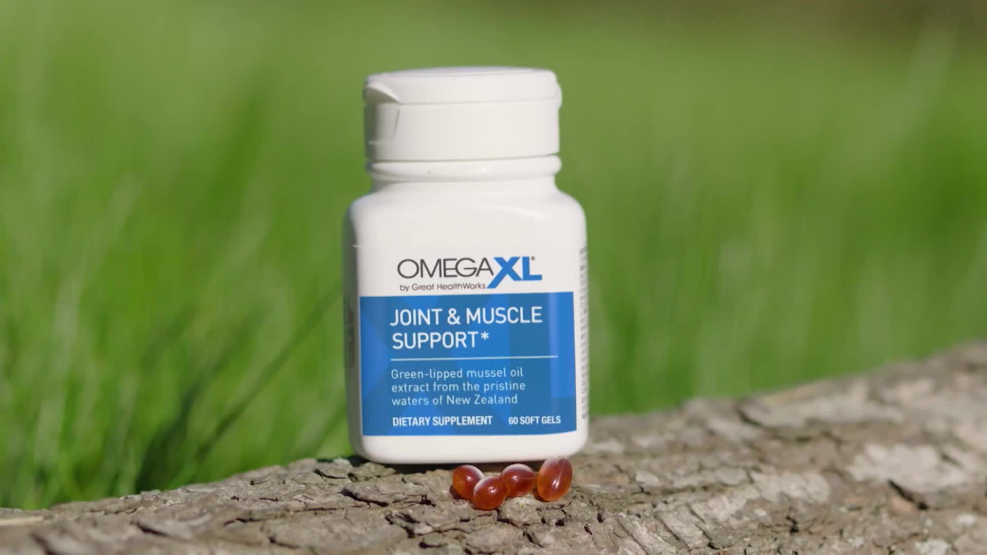 A white bottle of OmegaXL Joint & Muscle Support sits on a weathered log. Four amber soft gels rest in front of the bottle.