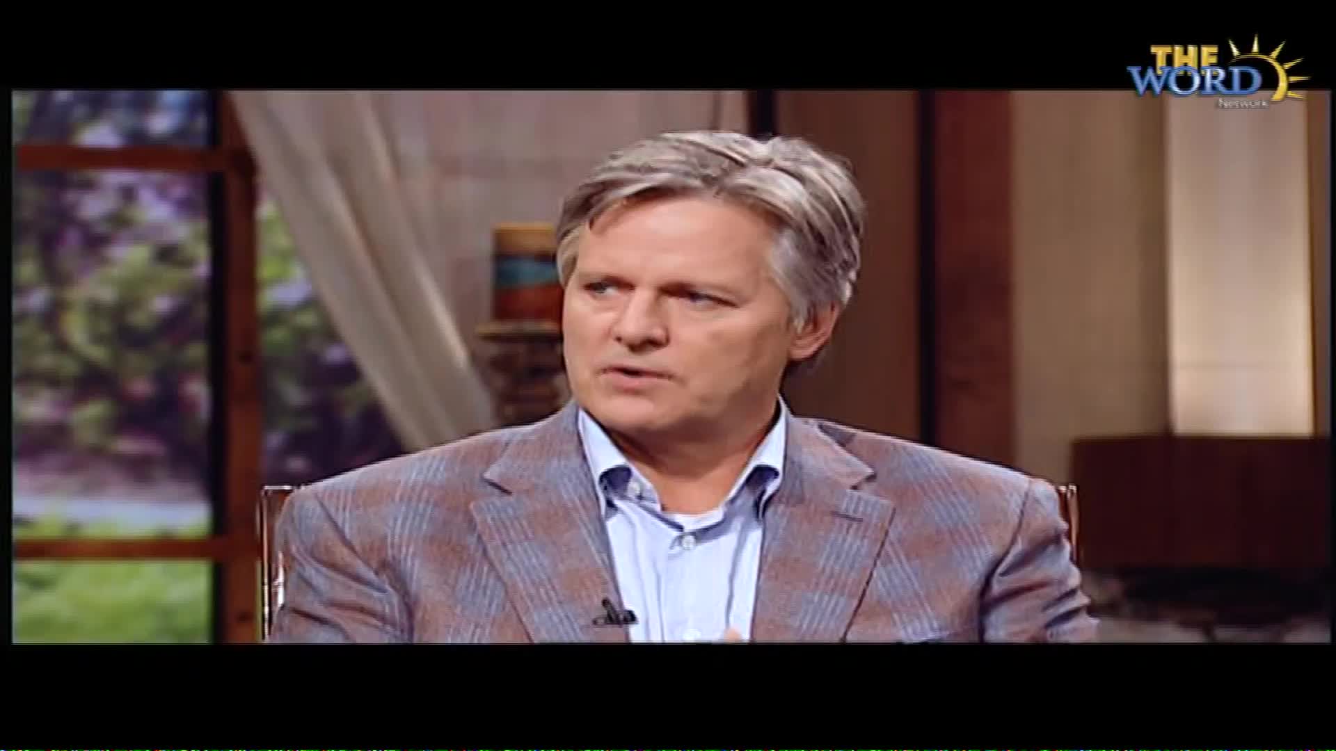 A man with graying hair, wearing a plaid jacket over a blue collared shirt, speaks directly to the camera. A logo for "The Word Network" appears in the upper right corner.