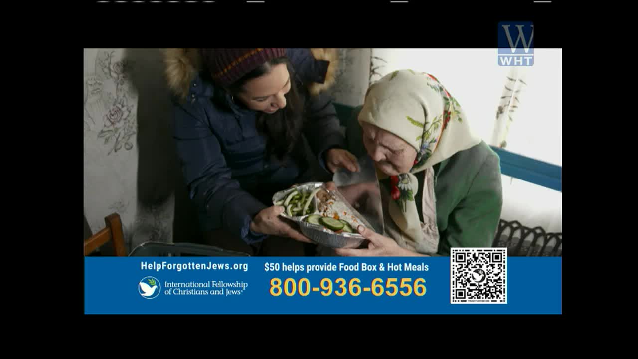 A younger woman offers a foil container of food to an older woman. The older woman, wearing a headscarf, leans in to look at the meal.