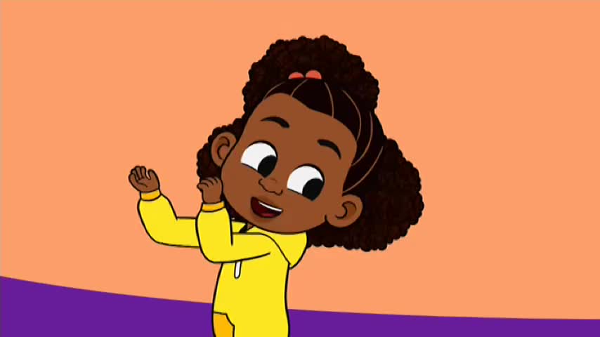 A smiling girl in a yellow hoodie is raising her hands, as if dancing. Her dark curly hair is tied back with a small pink bow.
