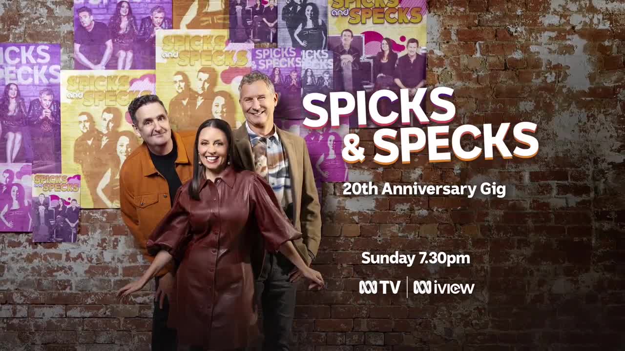 Three people stand in front of a brick wall, smiling. Behind them, posters advertise the ABC Australia show, "Spicks & Specks."
