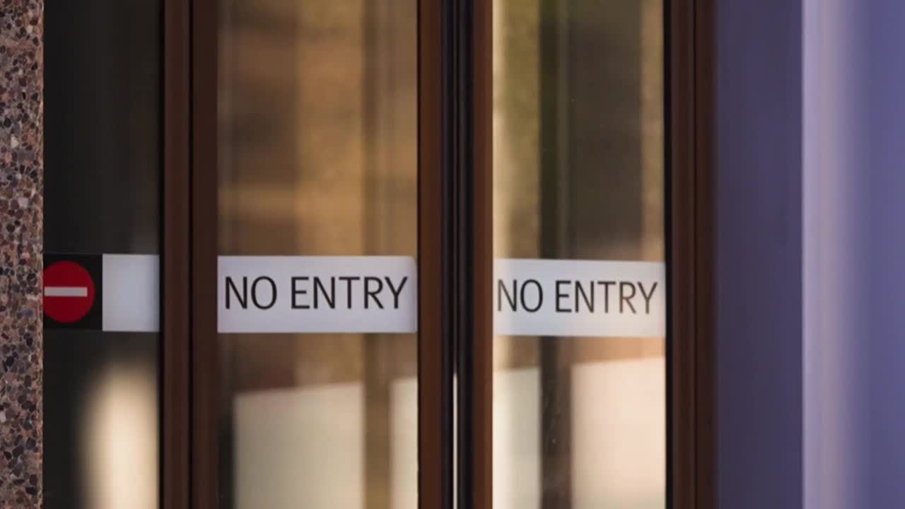 The glass doors are shut, each bearing a "NO ENTRY" sign. A red and white "do not enter" symbol is visible on the left door.
