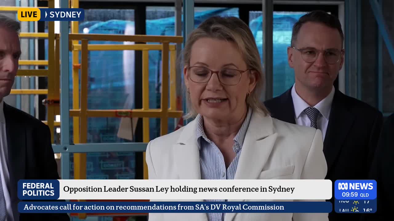 Sussan Ley, the Opposition Leader, is speaking into a microphone, her mouth moving as she addresses the press in Sydney. Behind her, a couple of men in suits stand, listening intently, as ABC News broadcasts live.
