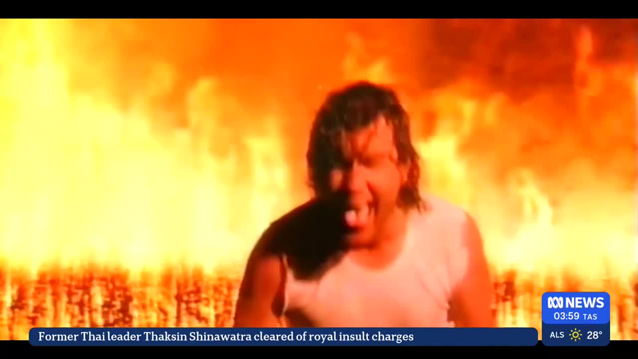 A man in a white tank top is screaming with his mouth open, his face illuminated by a wall of flames behind him. The ABC News logo is in the corner, reporting on the news from Australia.

